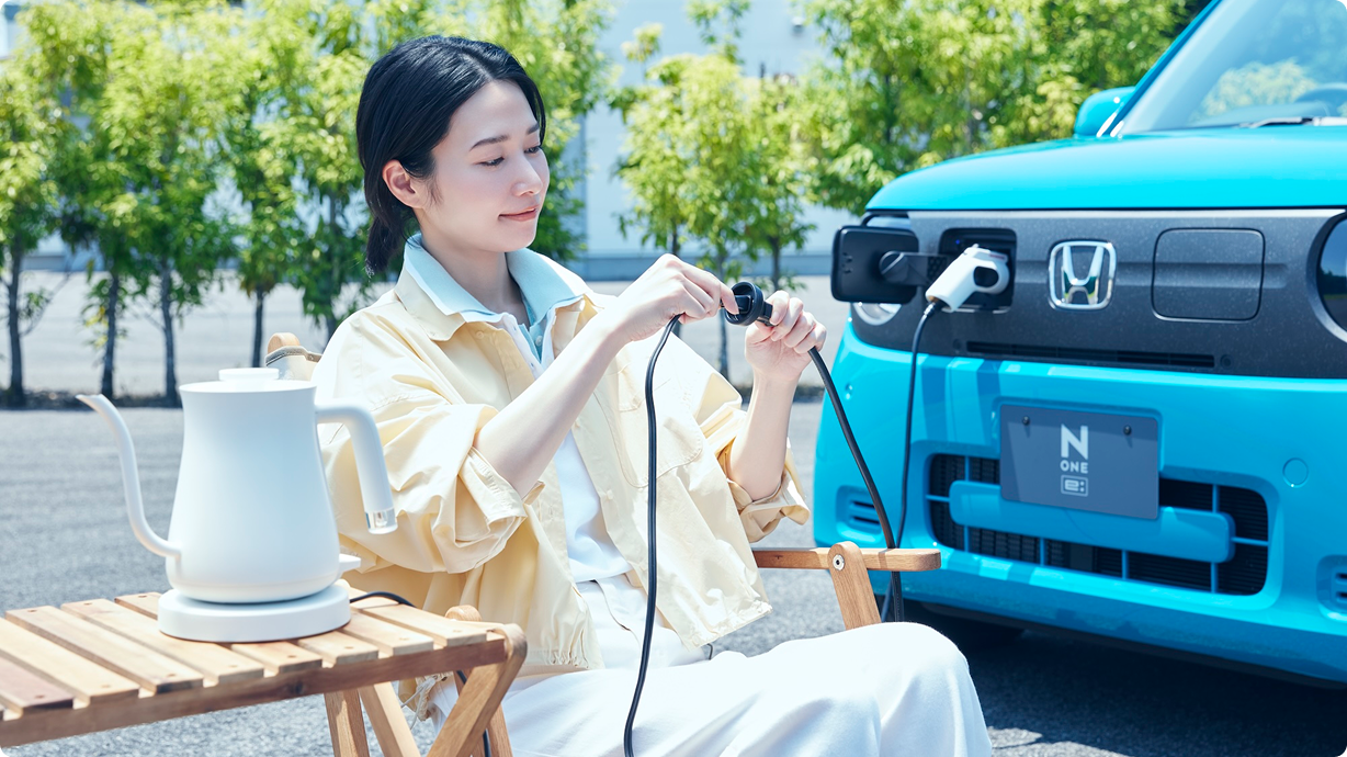女性がアウトドアで、N-ONE e:から給電しているイメージ